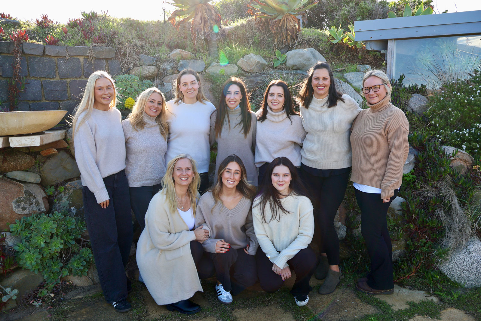 Embellish Beauty staff retreat. Ten females in beige tops and black pants gathered together